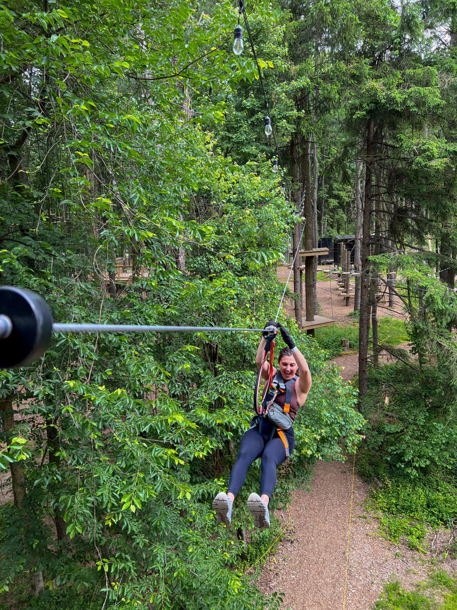 Woman ziplining through the trees at Tree Trails Trevose, PA